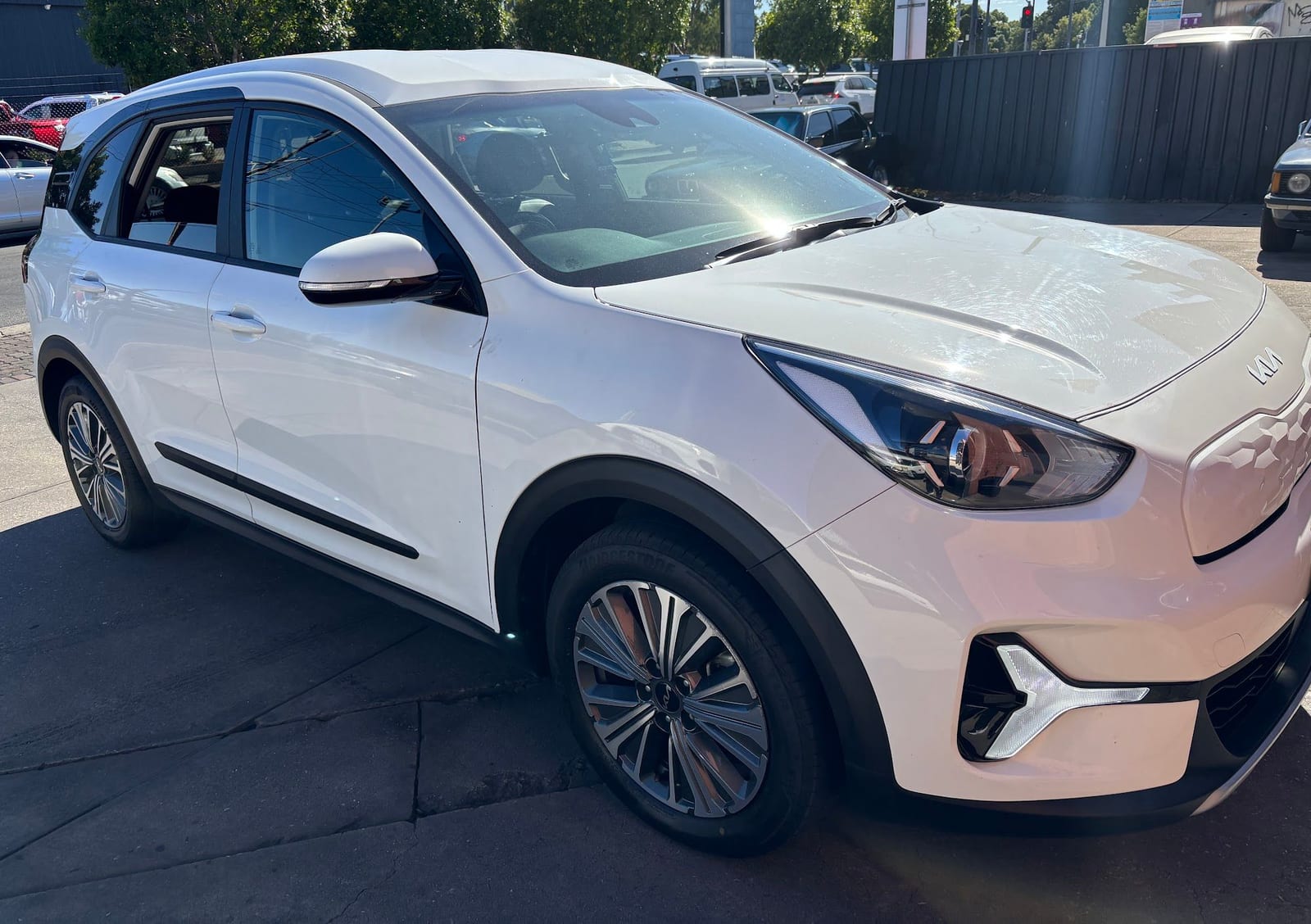 A white Kia SUV parked outside the garage