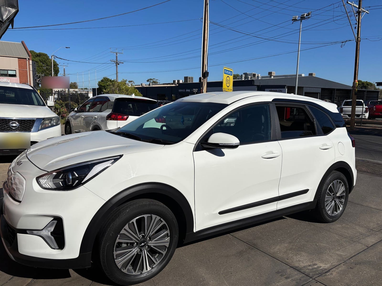 A white Kia SUV from the side on Prospect Road
